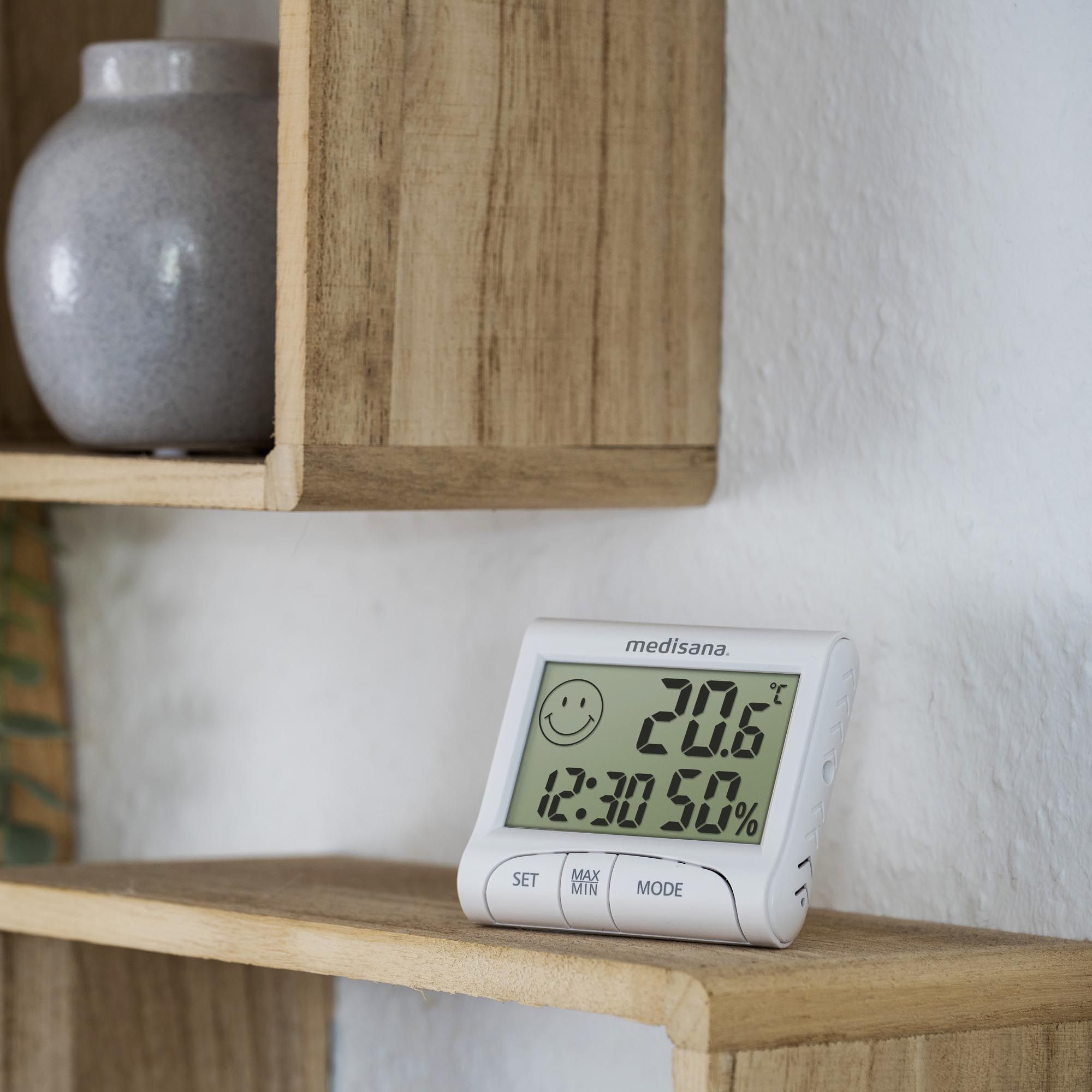 Igrometro digitale su una mensola di legno. Visualizza temperatura, ora e umidità. Marchio: medisana.