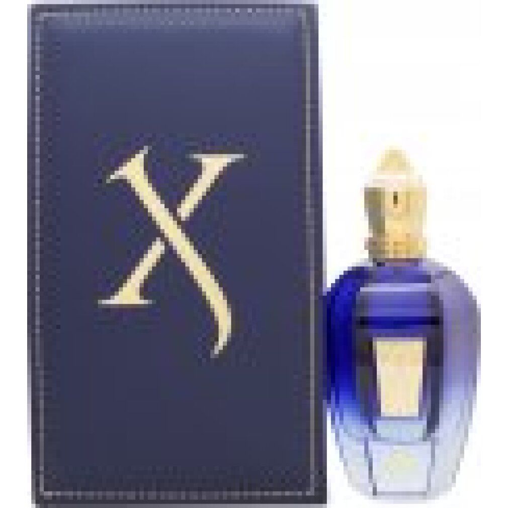 Flacone di profumo blu e oro accanto a una scatola blu con logo "X" dorato. Flacone con tappo dorato.