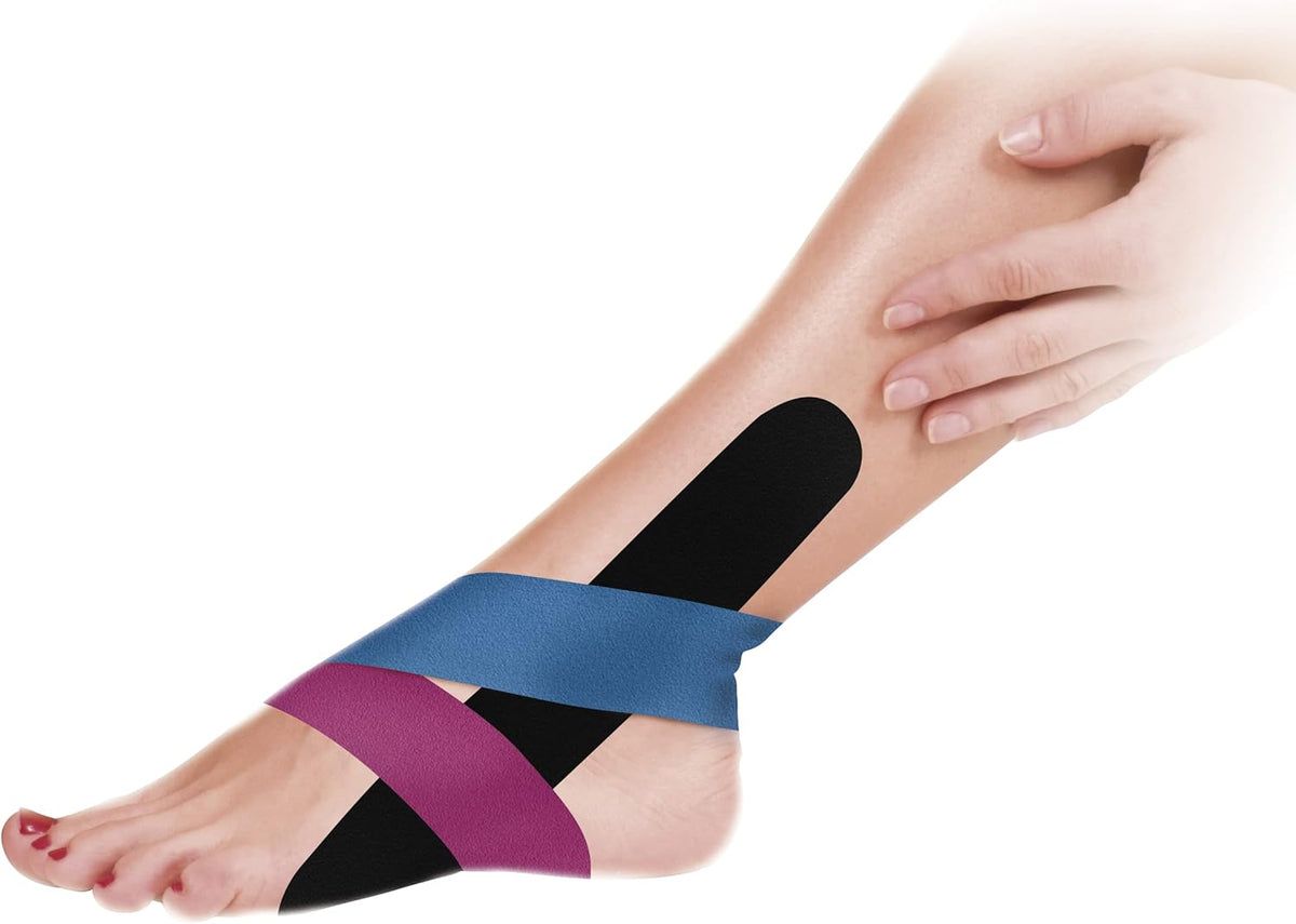 Piede con cerotti kinesio rosa, blu e neri. I cerotti sono applicati sul piede e sulla caviglia. Una mano tocca il piede.