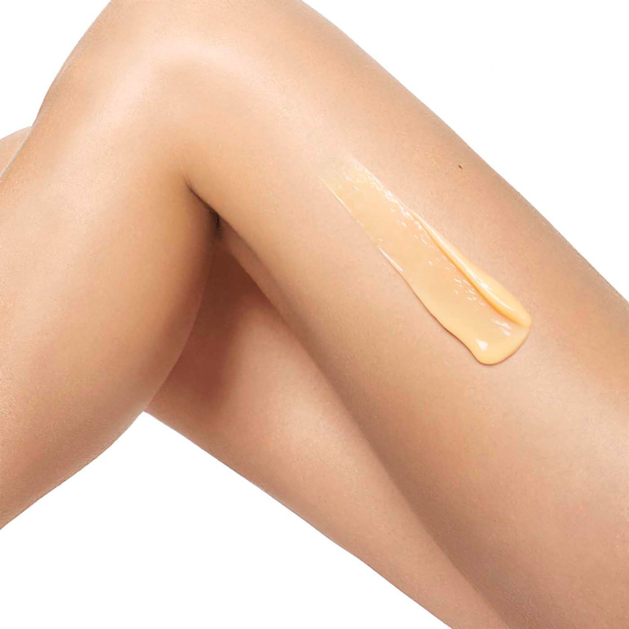 Gambe con crema gialla applicata. La crema è visibile sulla pelle.