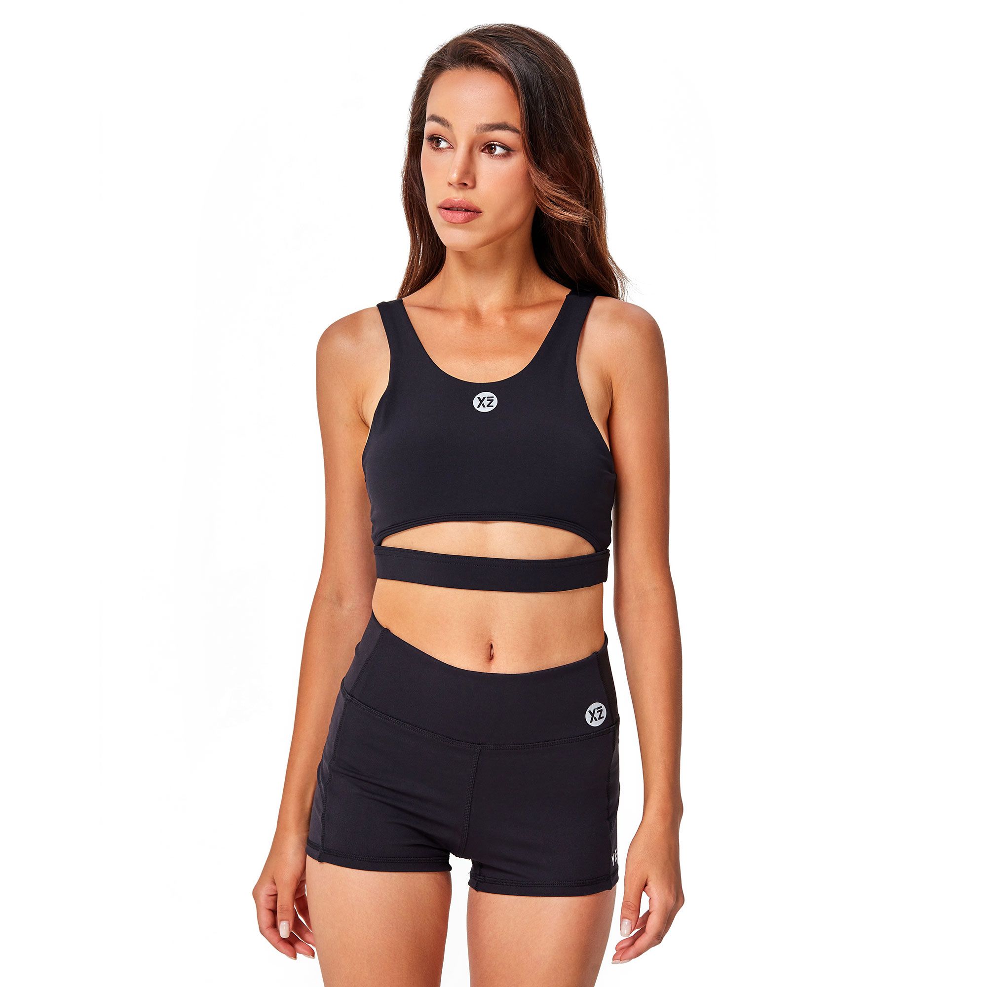 Reggiseno sportivo nero con cut-out e pantaloncino coordinato. Entrambi i capi presentano un logo bianco.