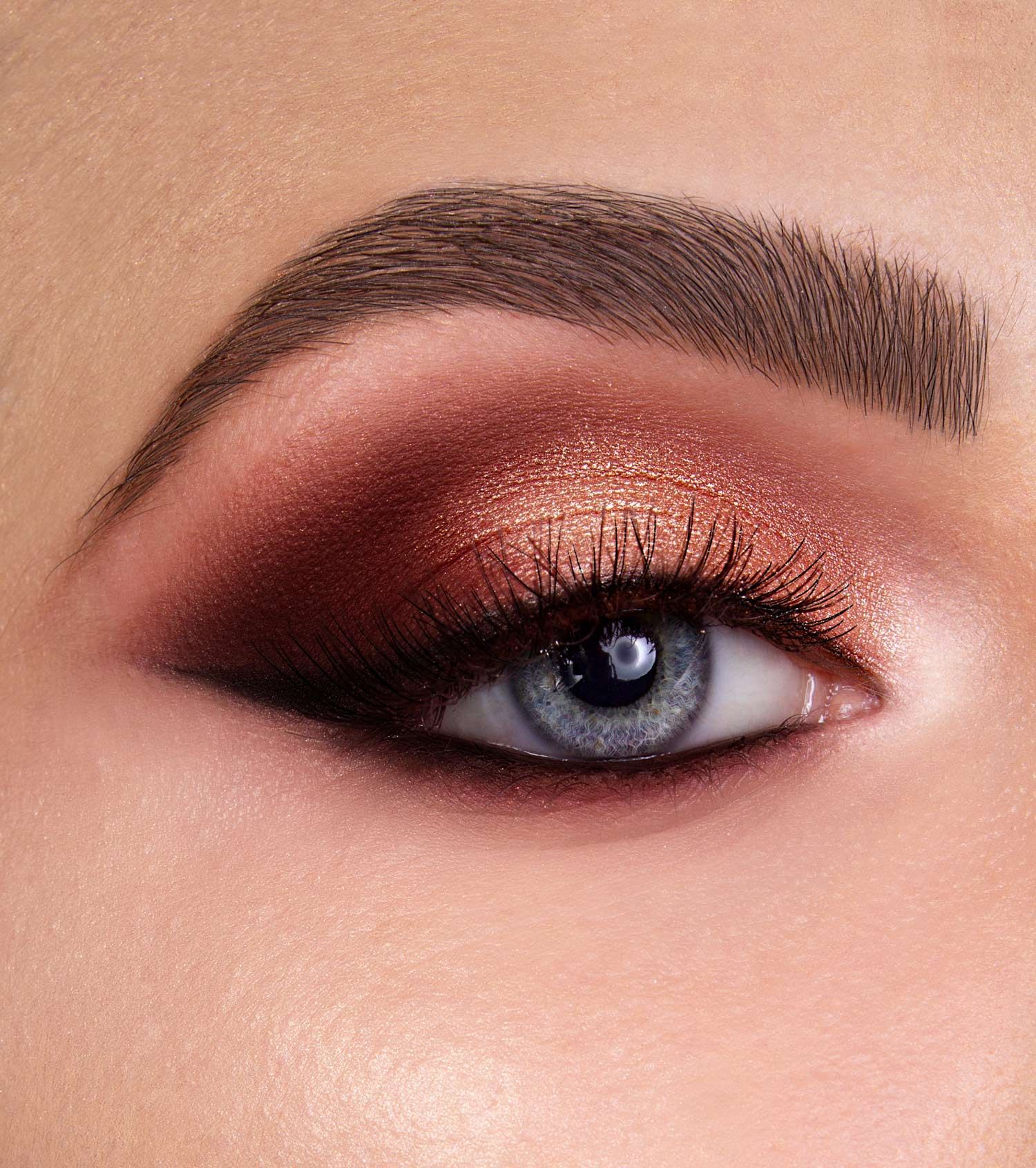Un occhio con ombretto color rame e marrone, eyeliner e ciglia lunghe.