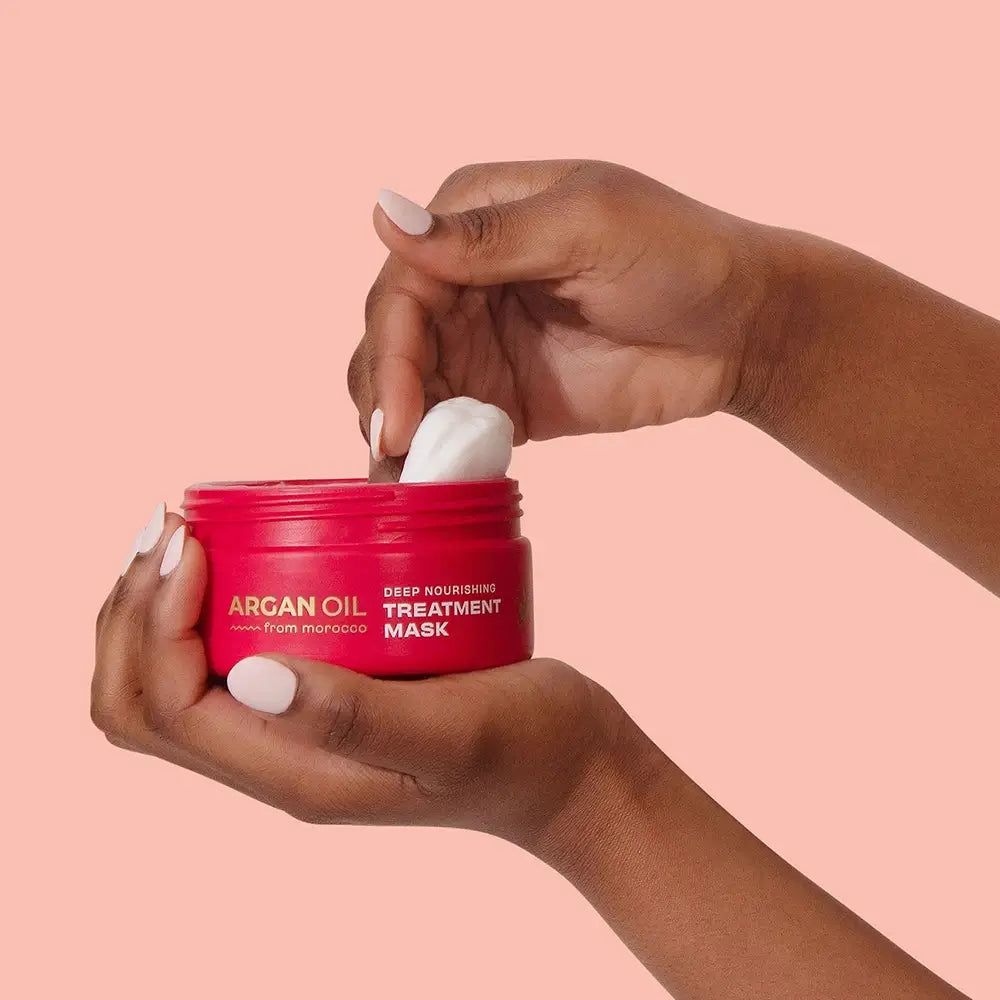 Mani che aprono un vasetto rosso di maschera trattamento nutriente profondo all'olio di argan.
