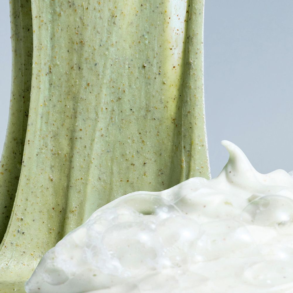 Primo piano di sostanza verde gelatinosa e schiuma bianca. La sostanza verde contiene particelle scure.