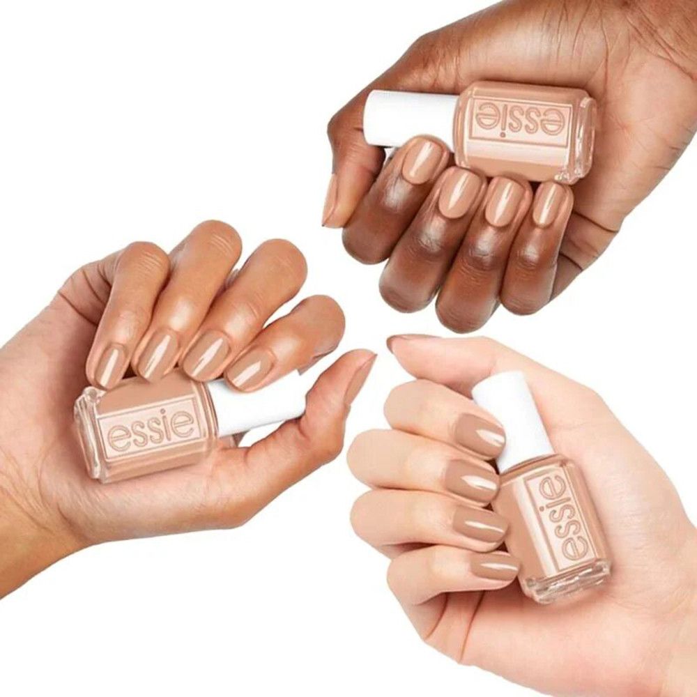 Tre mani che tengono flaconi di smalto e unghie smaltate. Tonalità beige rosata. Marchio Essie visibile.