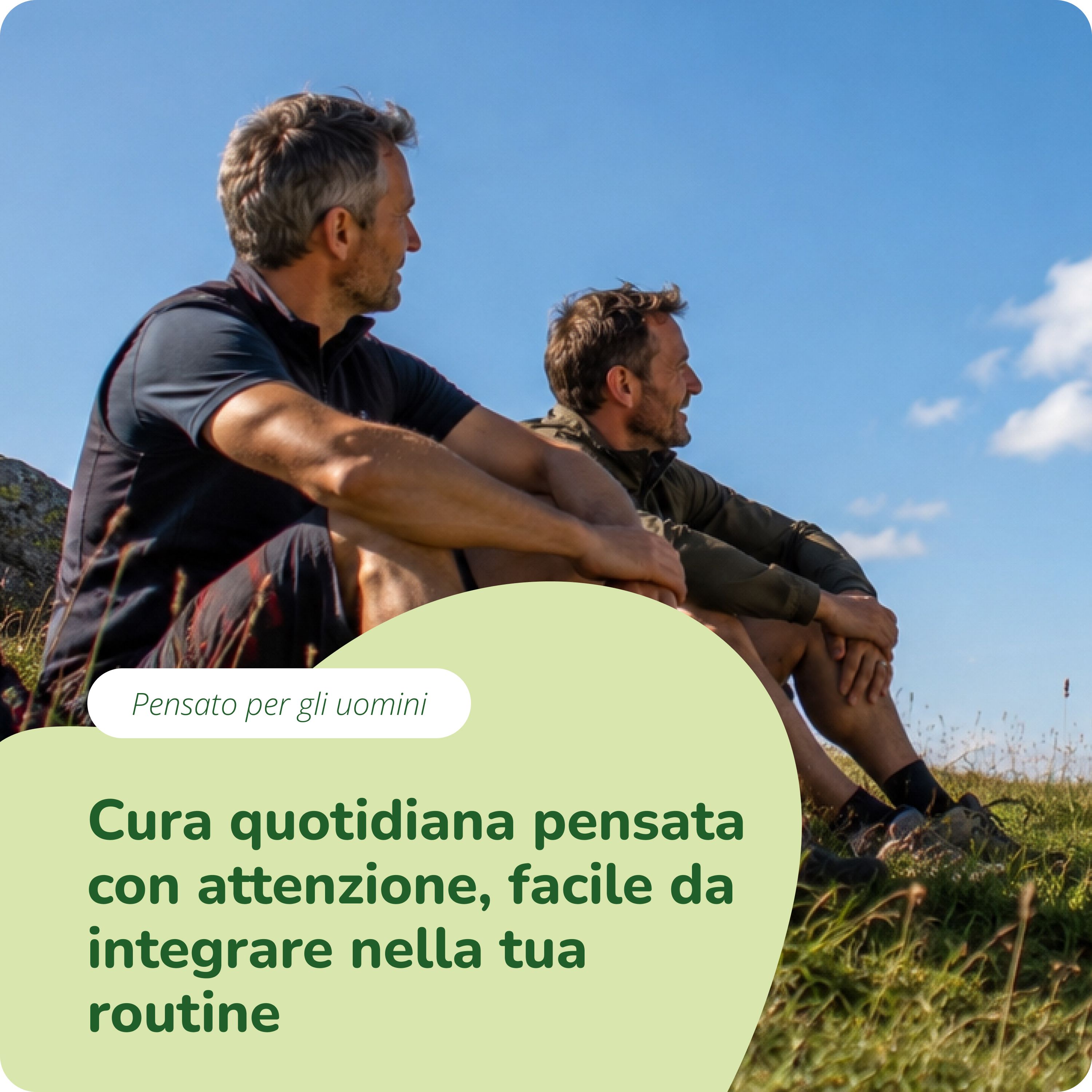 Due uomini seduti su una collina guardano in lontananza.