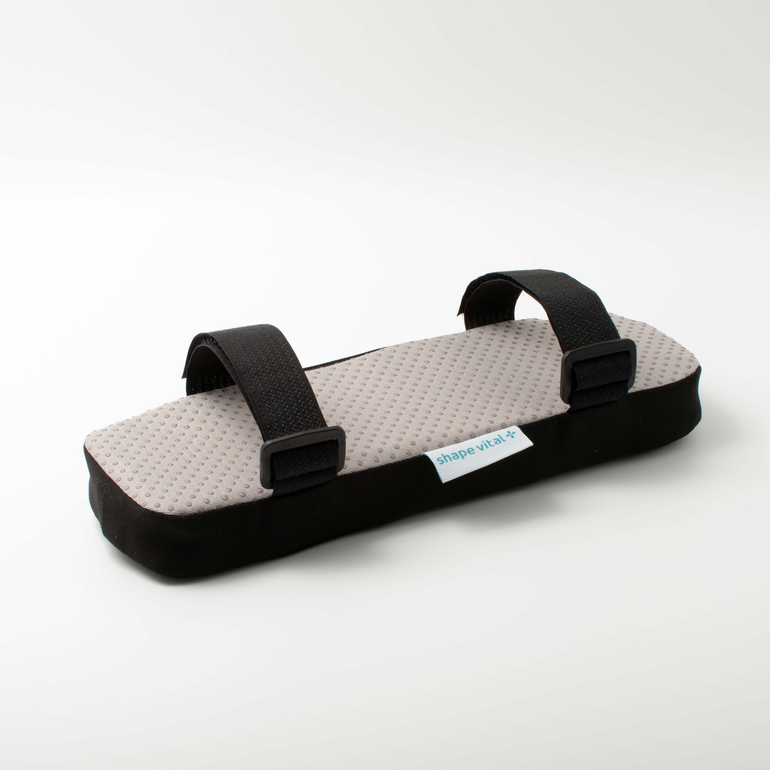 Cuscino per bracciolo con superficie grigia a pois e bordo nero. Cinghie nere con clip. Etichetta 'shape vital+'.