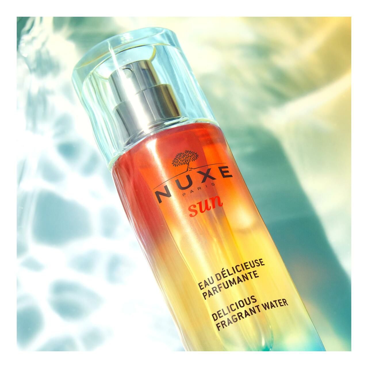 Flacone Nuxe Sun Eau Délicieuse Parfumante con erogatore. Gradiente di colore da arancione a giallo.