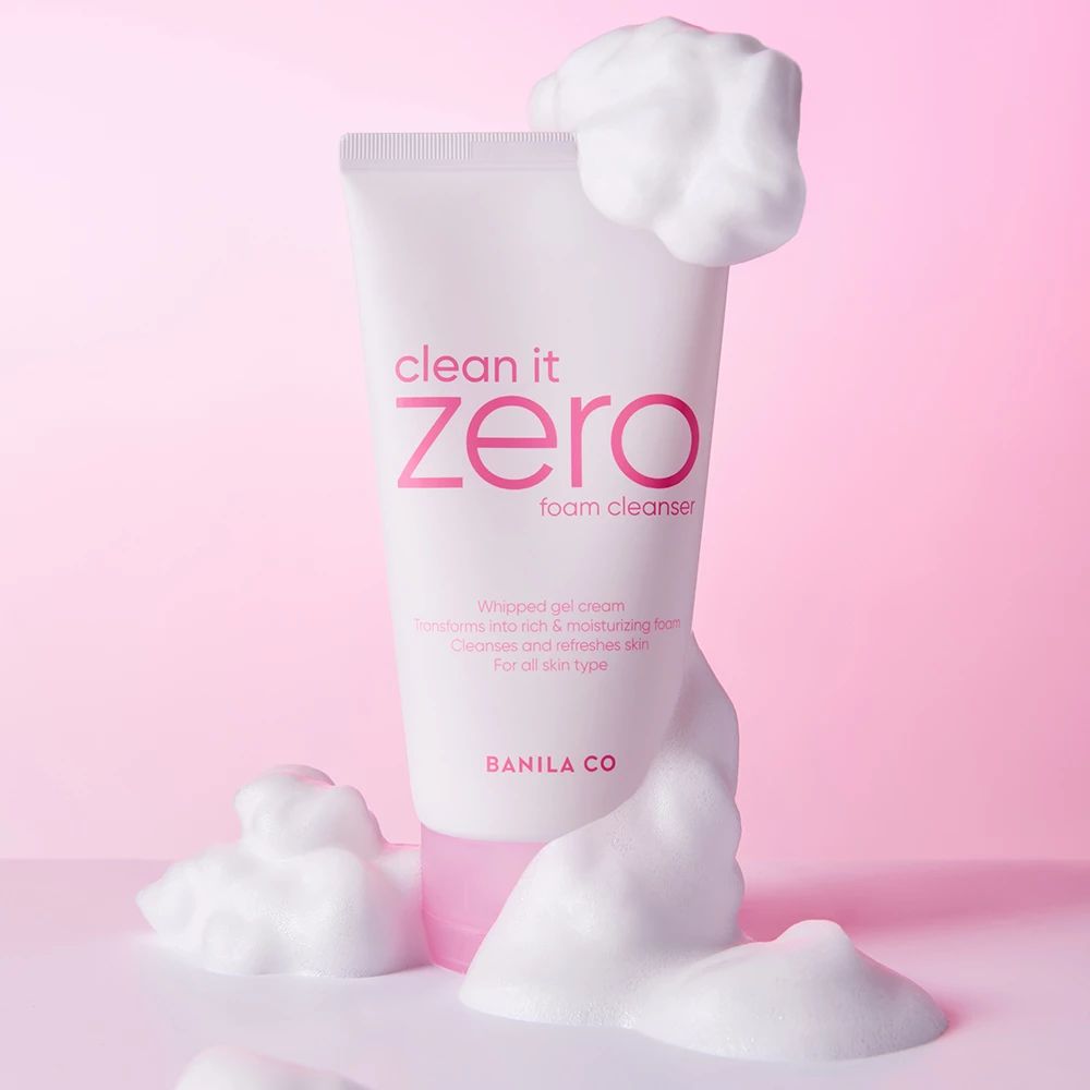 Tubo bianco con dettagli rosa e scritta "clean it zero foam cleanser". Schiuma avvolge il tubo. Logo BANILA CO.
