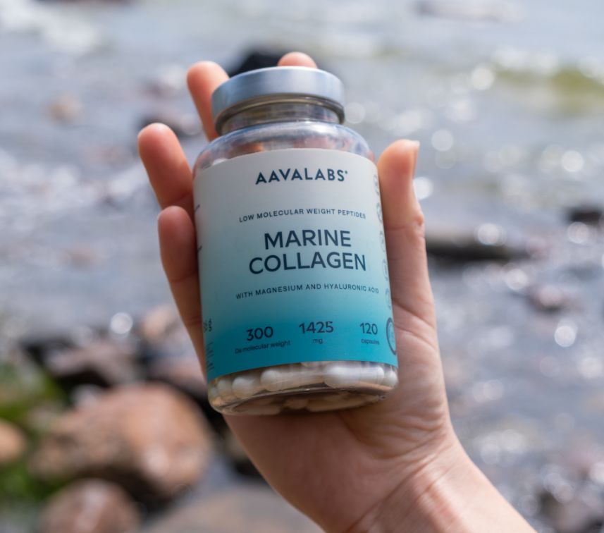 Mano che tiene una bottiglia di Aavalabs Marine Collagen vicino all'acqua.