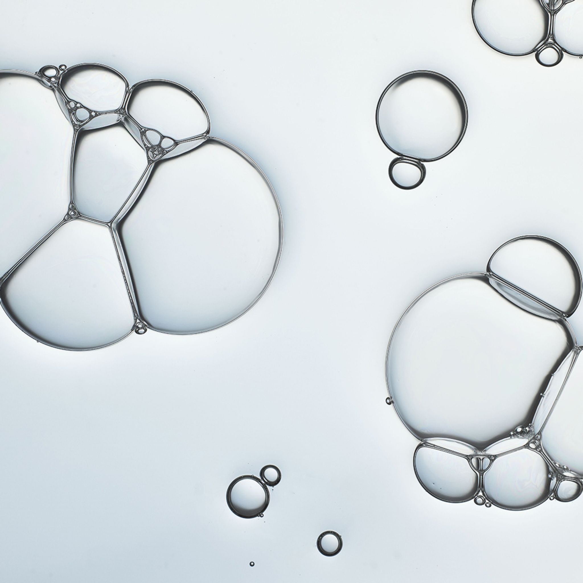 Primo piano di bolle di sapone. Diverse bolle trasparenti di varie dimensioni su sfondo chiaro.