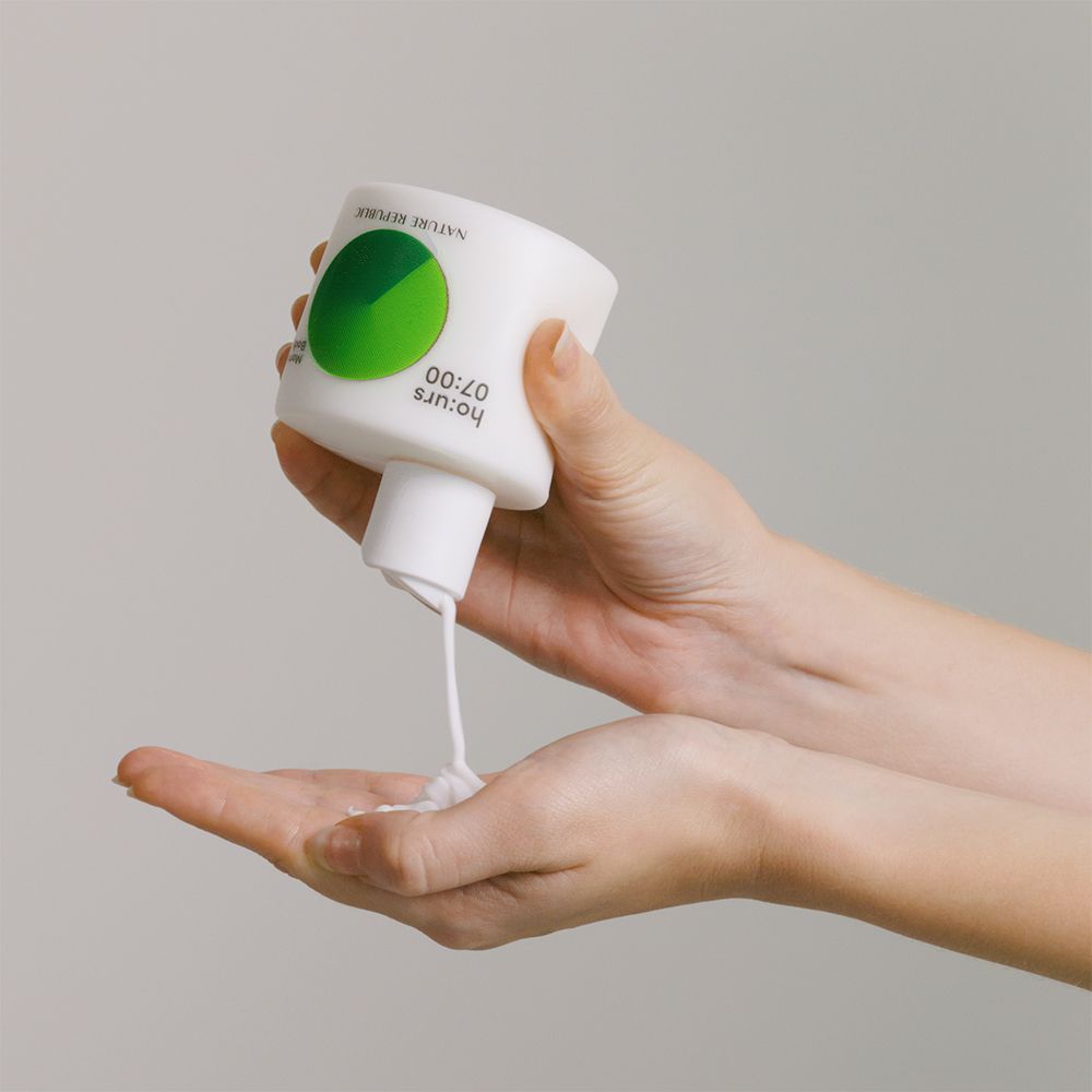 Flacone bianco, prodotto versato nella mano. Cerchio verde sul flacone. Pelle chiara.