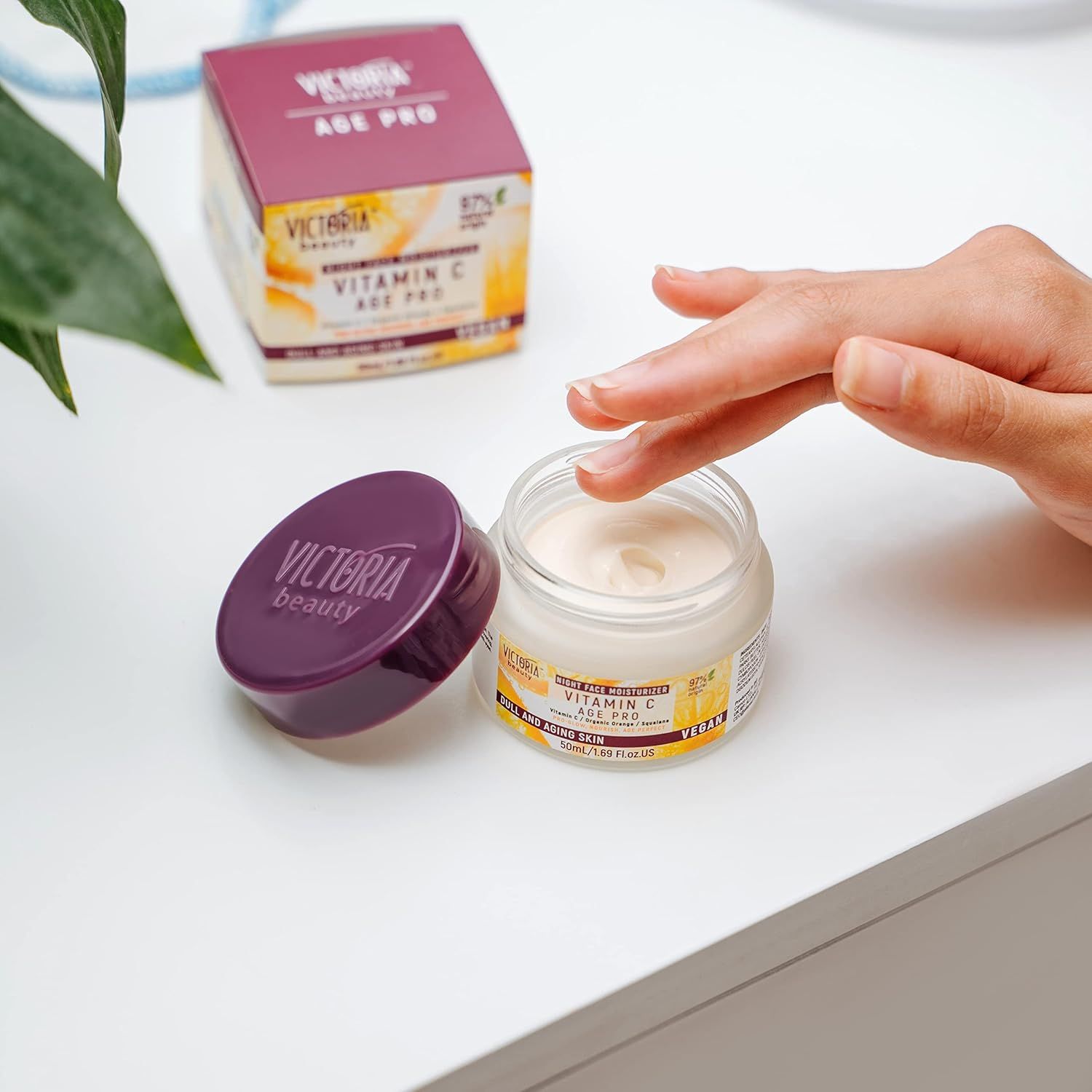 Vaso di crema aperto e coperchio. Scritta Victoria Beauty. Scatola con scritta Vitamin C Age Pro.