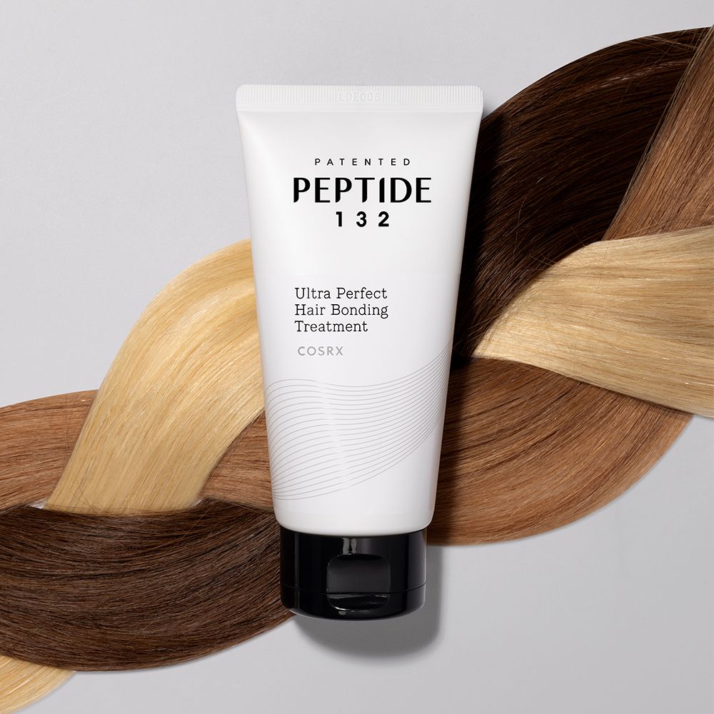 Tubo bianco con tappo nero, circondato da ciocche di capelli di vari colori.