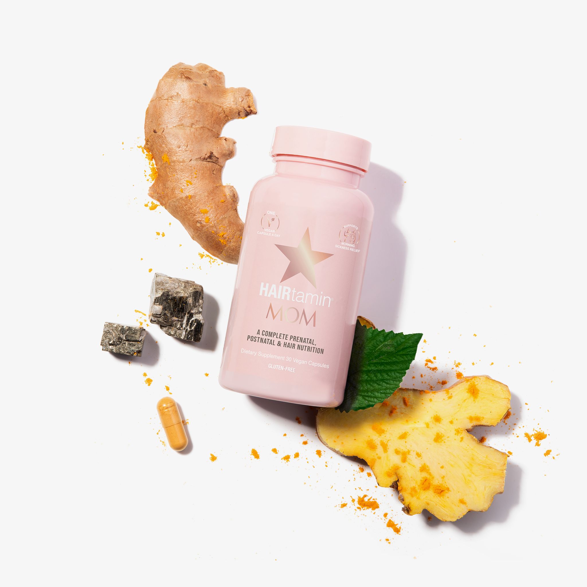 Flacone rosa HAIRtamin MOM con zenzero, curcuma e foglie. Capsula accanto.