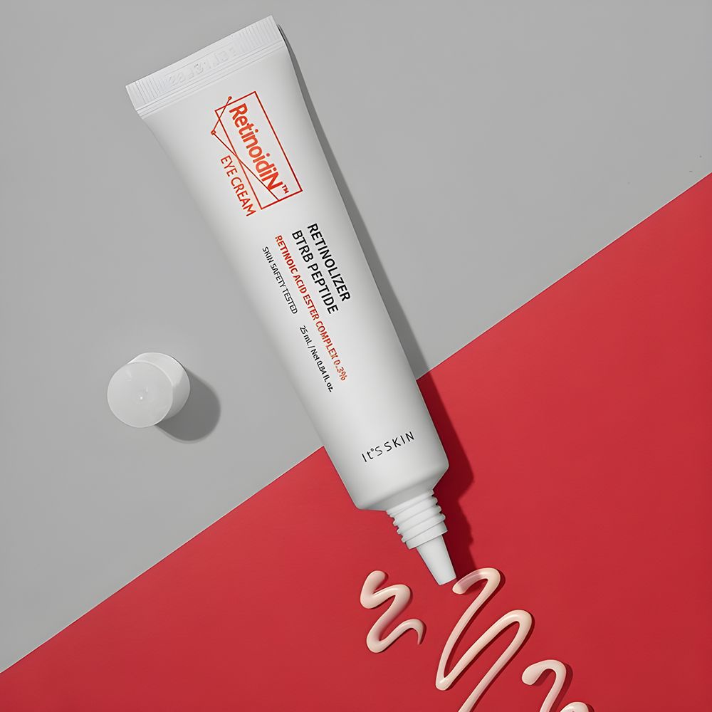 Tubo bianco con logo e testo arancione. Nome prodotto: Retinoidin Eye Cream. Traccia di crema su sfondo rosso.