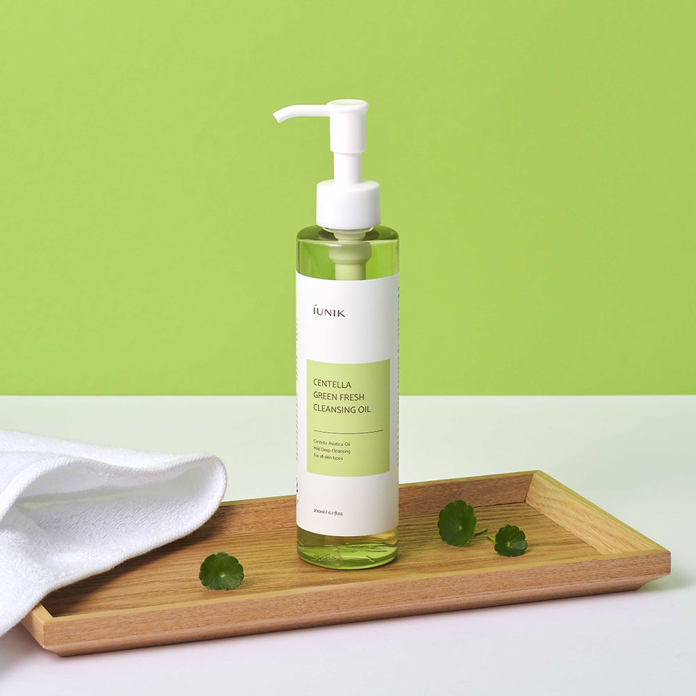Olio detergente iUNIK Centella Green Fresh su vassoio di legno con asciugamano.