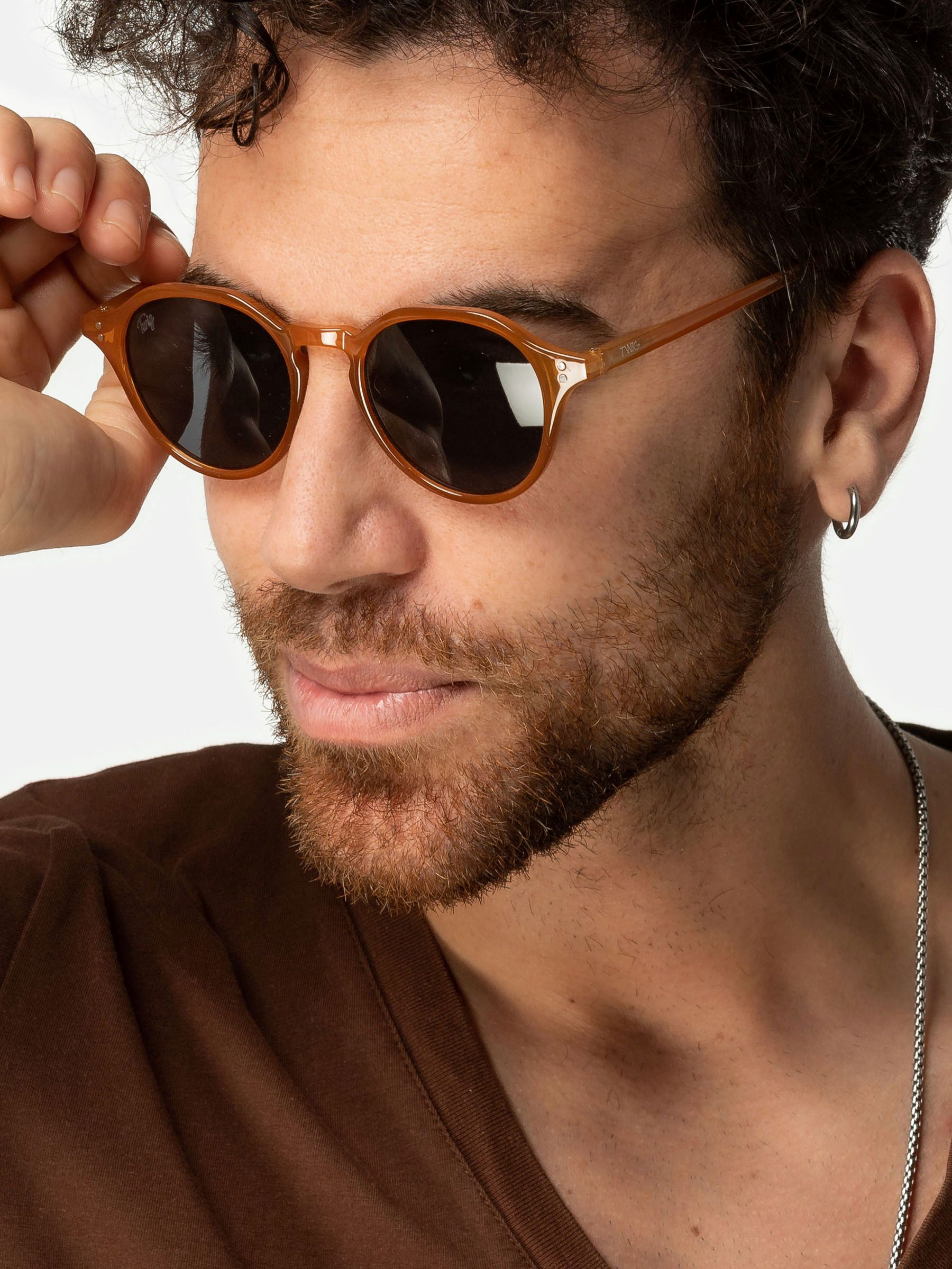 Uomo con occhiali da sole Twig Honey Orange. Montatura marrone, lenti scure.