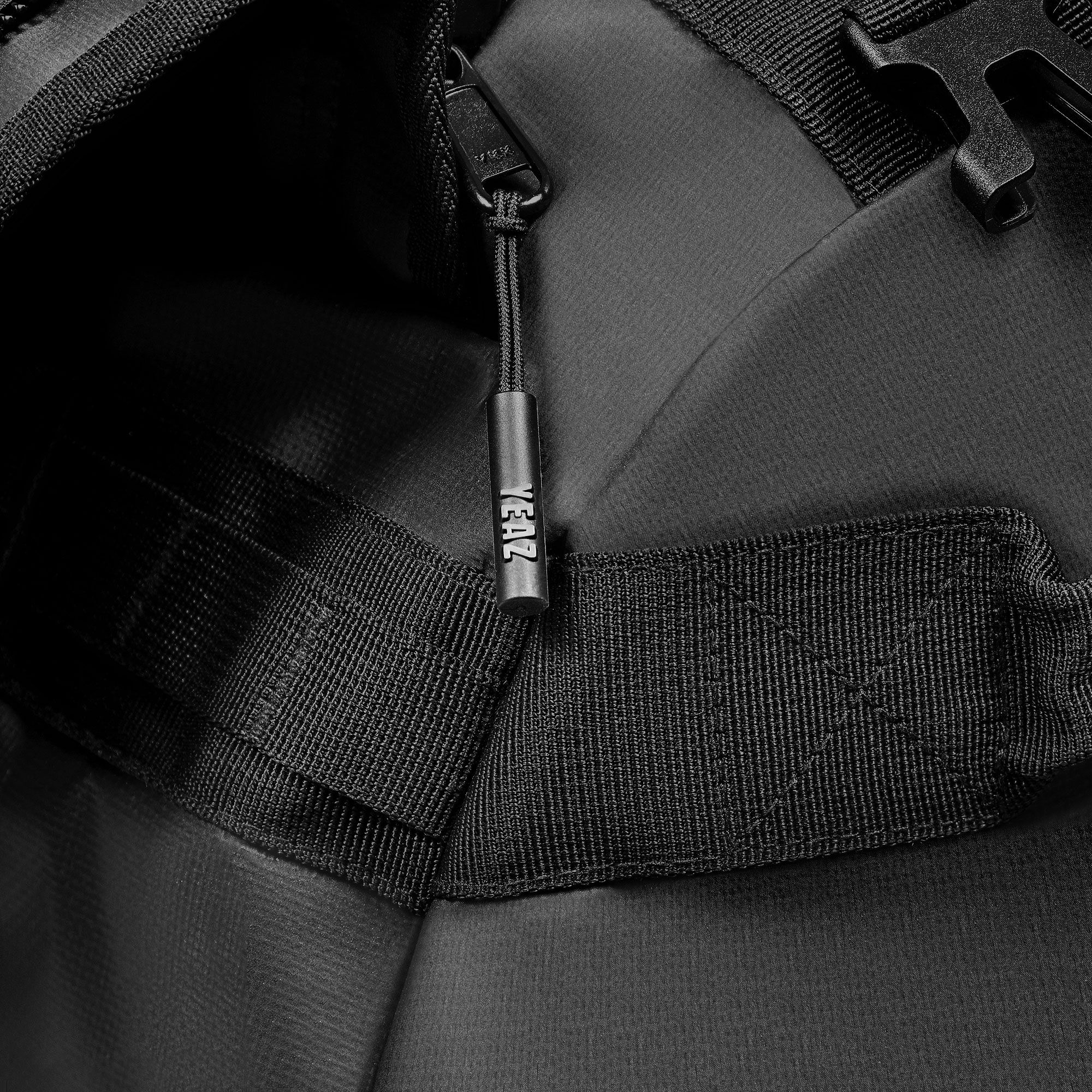 Primo piano di una cerniera su una borsa sportiva nera. Il cursore ha la scritta YEAZ.