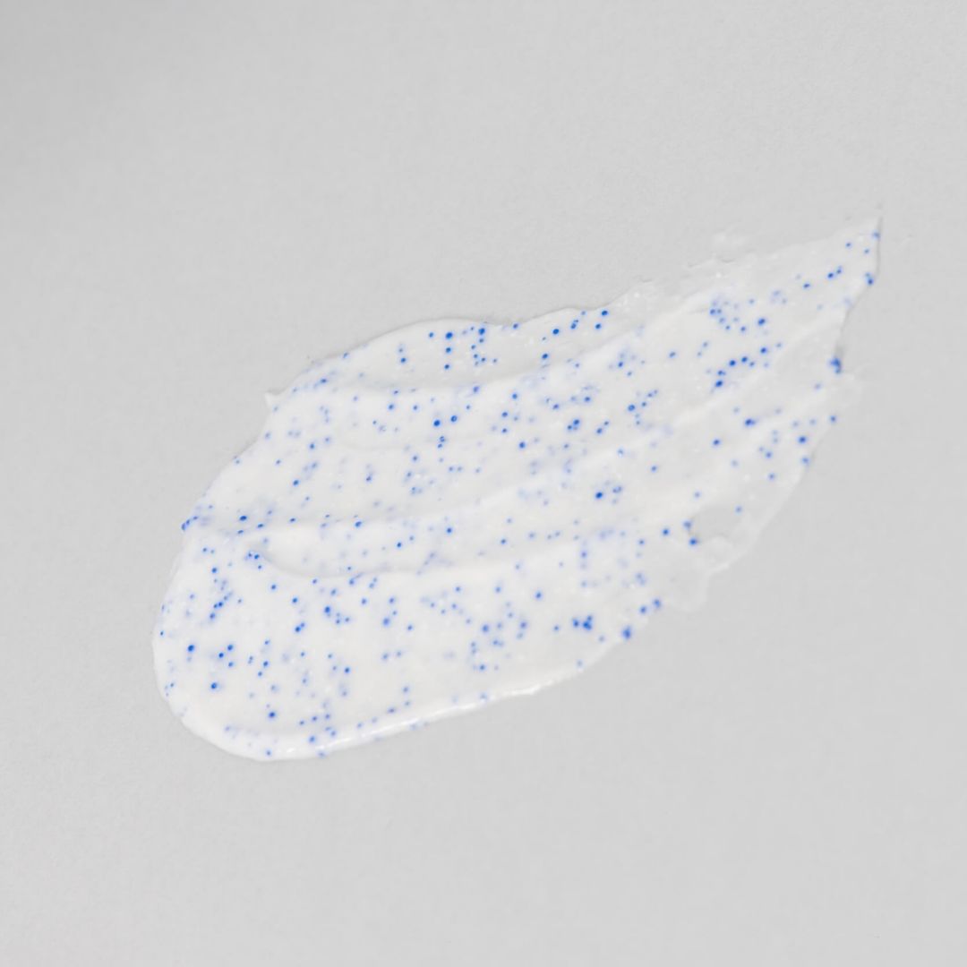 Scrub bianco con particelle blu su sfondo grigio.