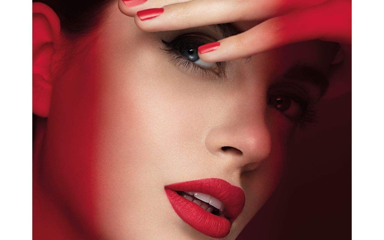 Rossetto rosso sulle labbra. Donna con smalto rosso. Tonalità rossa sul viso.