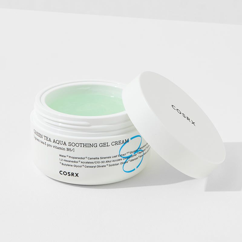Vasetto bianco con coperchio aperto. Prodotto verde-gel visibile. Scritta 'Green Tea Aqua Soothing Gel Cream' e 'COSRX'.
