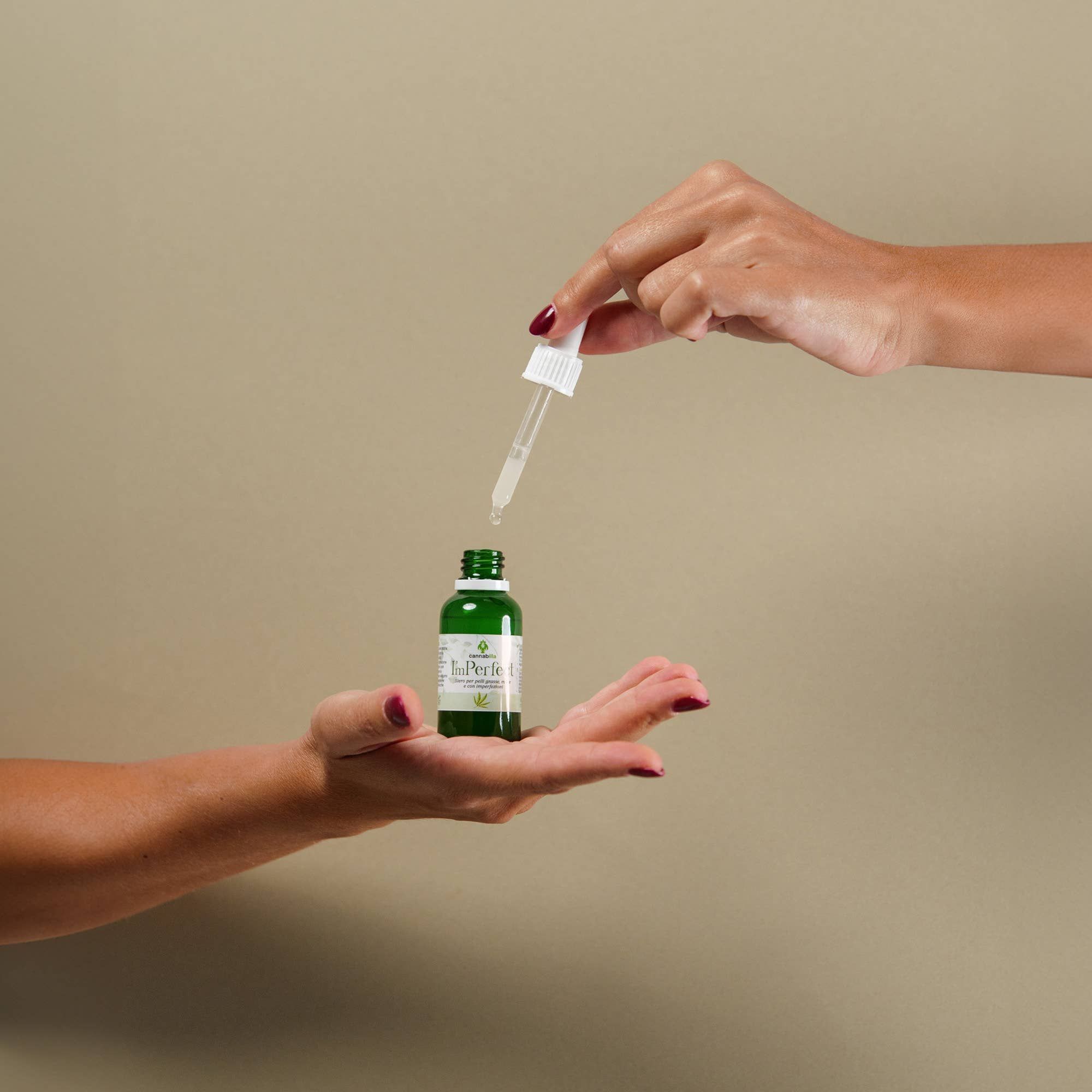 Due mani tengono un flacone verde con contagocce. Scritto: ImPerfect, Siero Viso Purificante alla Canapa. Gocce che cadono.