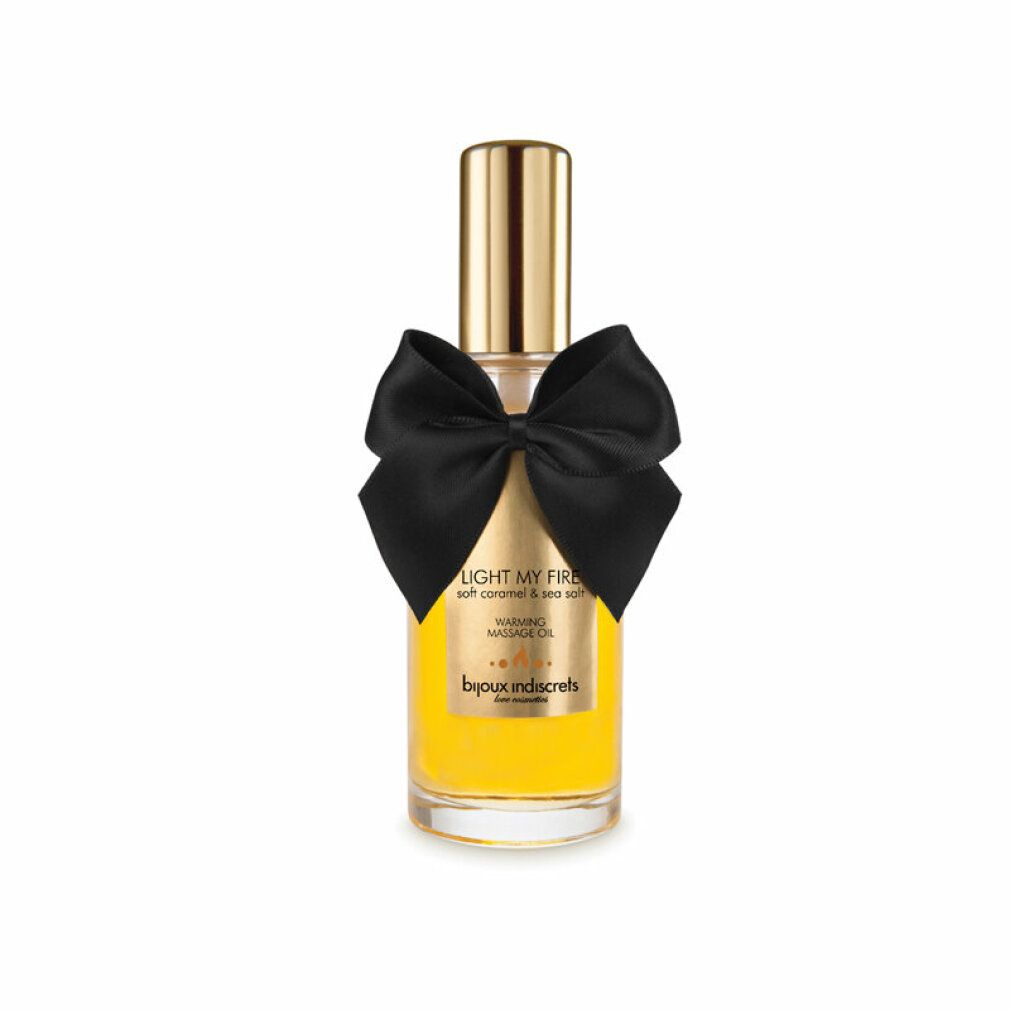 Flacone in vetro con tappo dorato, liquido giallo e fiocco nero. Scritta: Light My Fire, Warming Massage Oil.