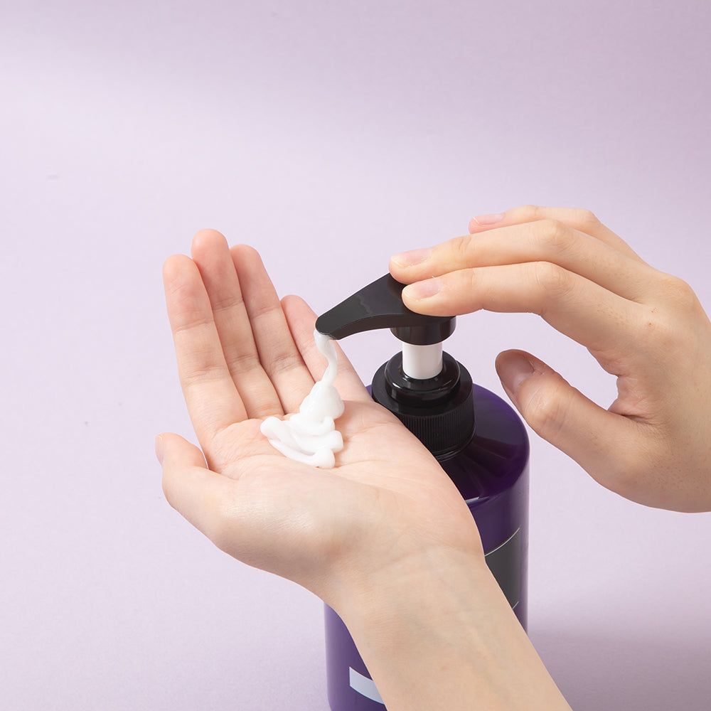 Mani che premono KUNDAL Honey & Macadamia Protein Treatment da un flacone spray.