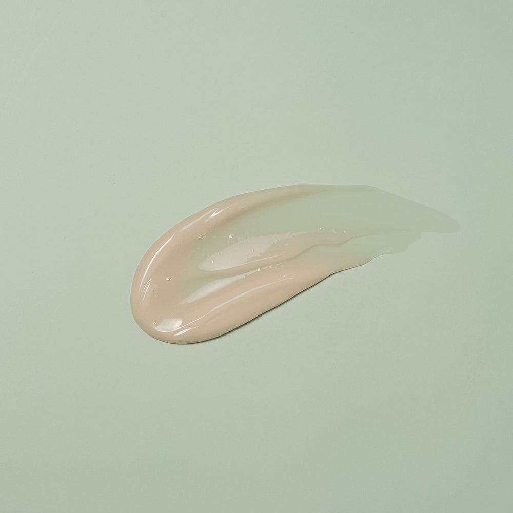 Macchia di crema chiara su sfondo verde chiaro.