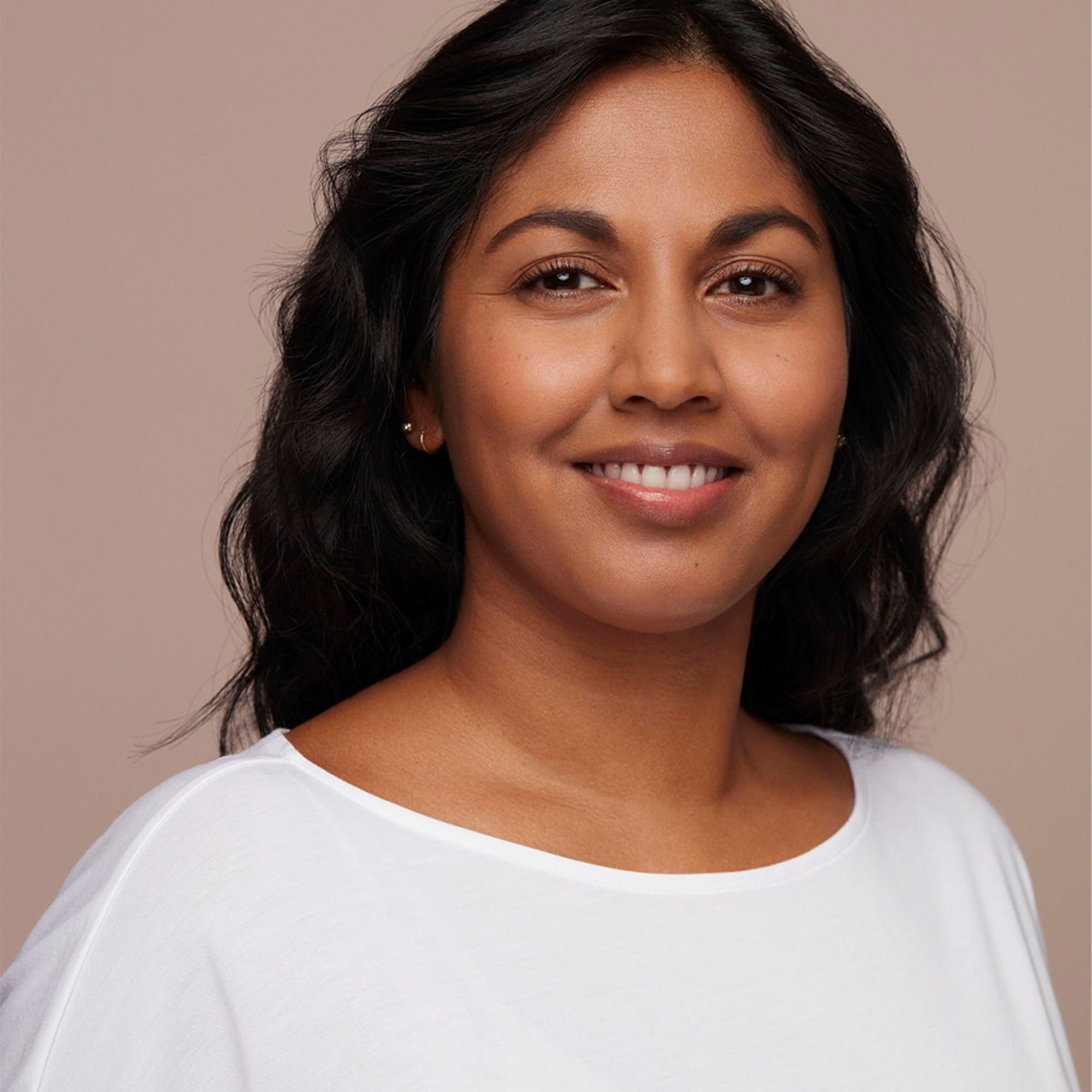 Ritratto di donna sorridente con capelli scuri. Indossa un top bianco.