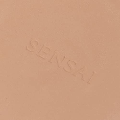 Primo piano di un compatto di polvere beige chiaro. La scritta Sensai è in rilievo.