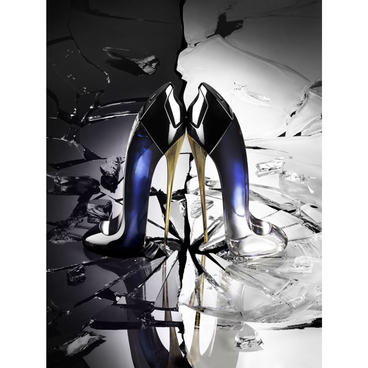 Due flaconi di profumo a forma di tacco alto su vetro rotto. Sfumatura nero-blu, tacco dorato. Riflesso.