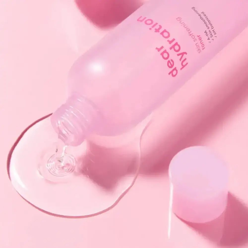 Flacone rosa "dear hydration skin softening toner" versa liquido. Il tappo è accanto.