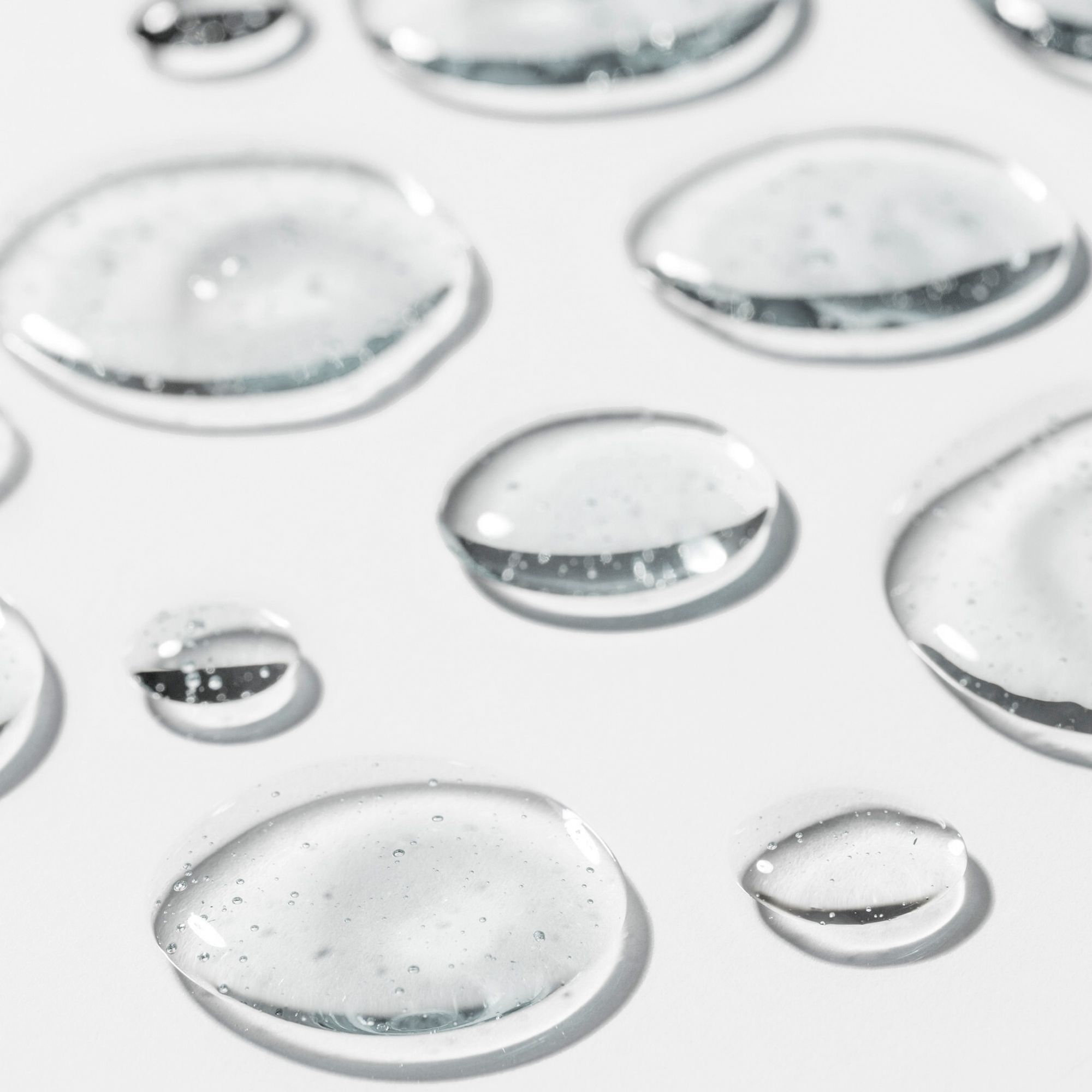 Diverse gocce trasparenti su sfondo bianco. Primo piano.