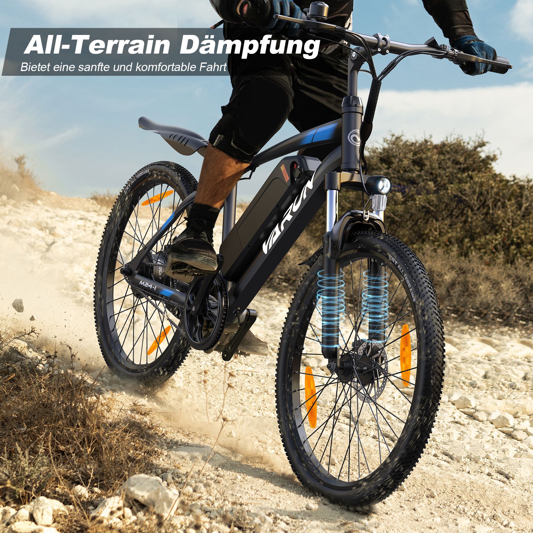 E-bike in movimento su terreno accidentato. Visibili: VARUN, sospensioni, catarifrangenti arancioni, pneumatici neri.