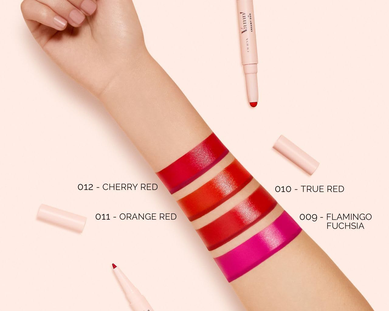 Braccio con campioni di rossetto. Colori: Cherry Red, Orange Red, True Red, Flamingo Fuchsia. Rossetti accanto.