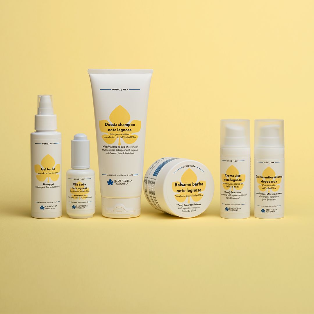 Diverse bottiglie e tubi bianchi con etichette gialle. Scritta: Balsamo Barba note legnose, gel doccia, crema viso.