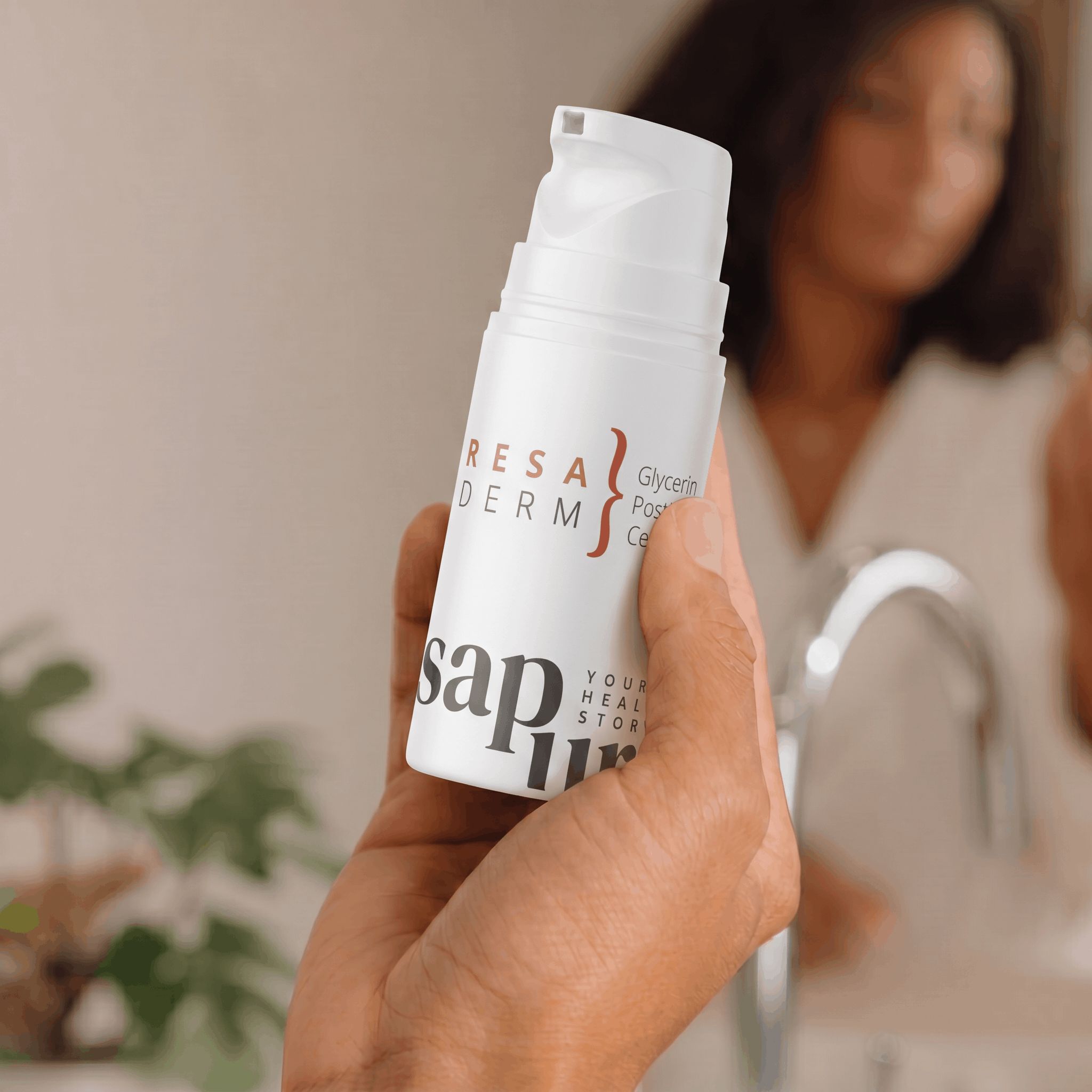 Una mano tiene un flacone bianco con pompa di crema per rosacea davanti a uno specchio del bagno.
