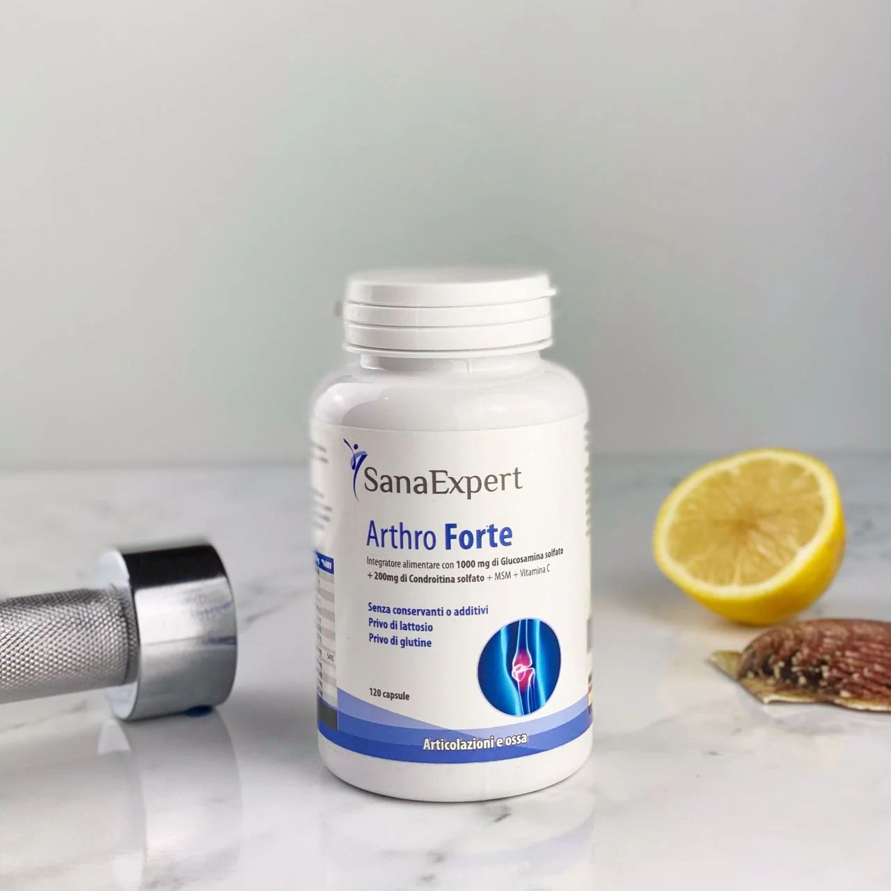 Flacone bianco SanaExpert Arthro Forte con 120 capsule. Accanto, un limone e un manubrio.
