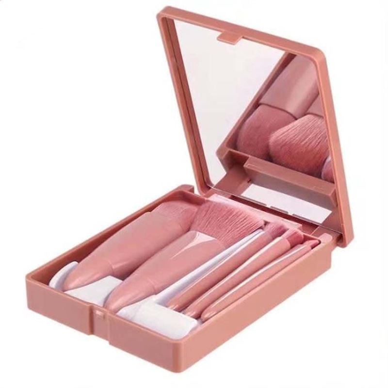 Set di pennelli da trucco da viaggio rosa con specchio nella custodia aperta.