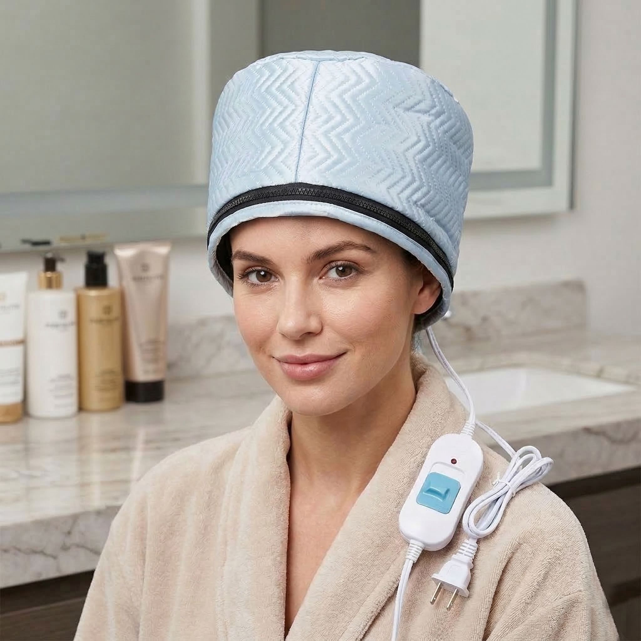 Donna con cuffia termica azzurra. Indossa un accappatoio. Prodotti per la cura sono visibili sullo sfondo.