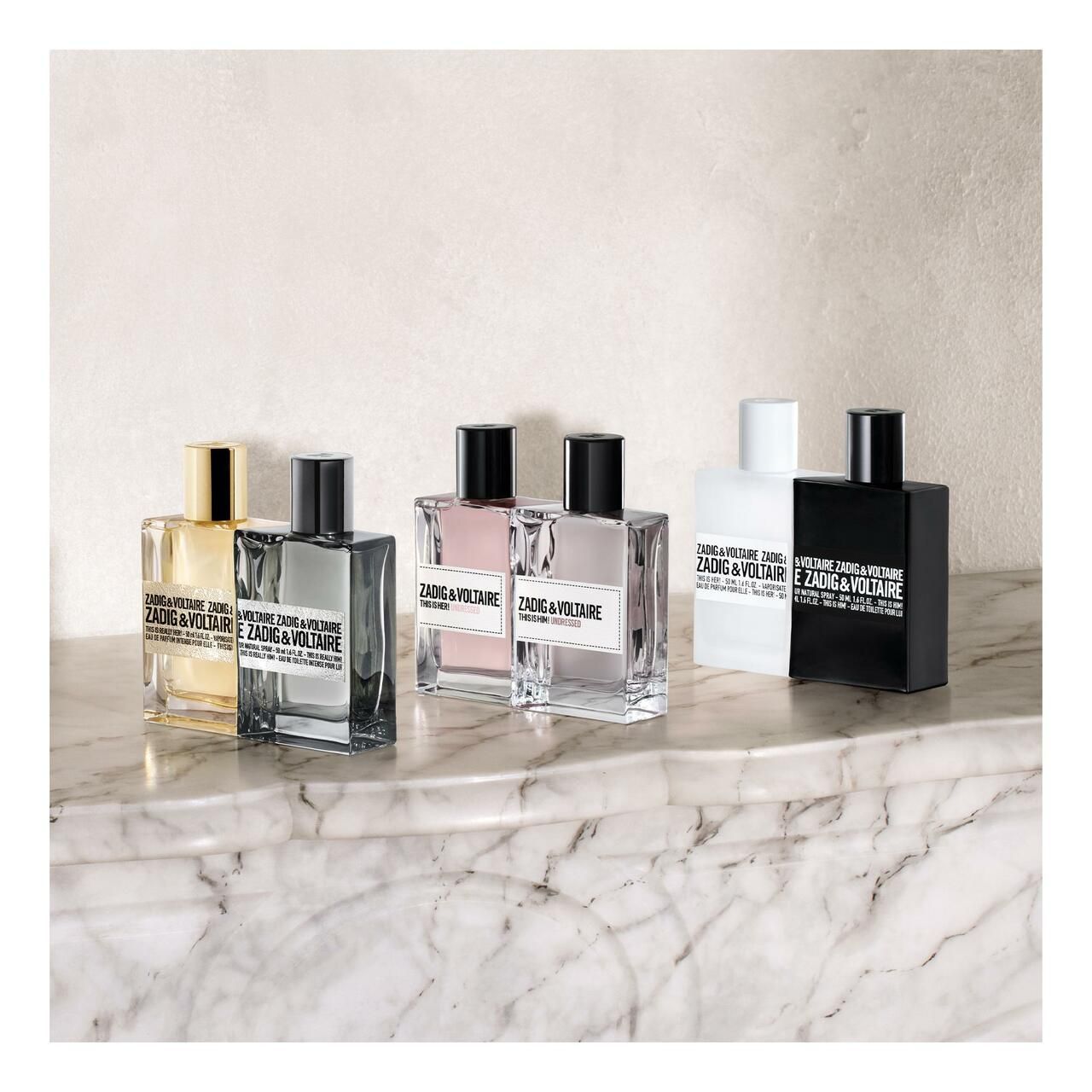 Sei flaconi di profumo di diversi colori. Scritta con nome del marchio e del prodotto. Su superficie in marmo.