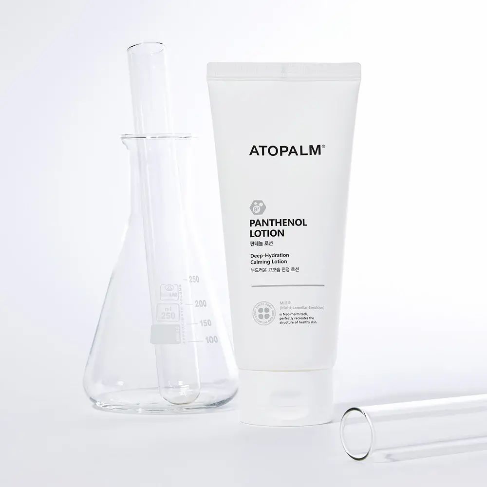 Tubo bianco ATOPALM Panthenol Lotion accanto ad attrezzature di laboratorio. Testo inglese e coreano. Logo e testo. Sfondo bianco.
