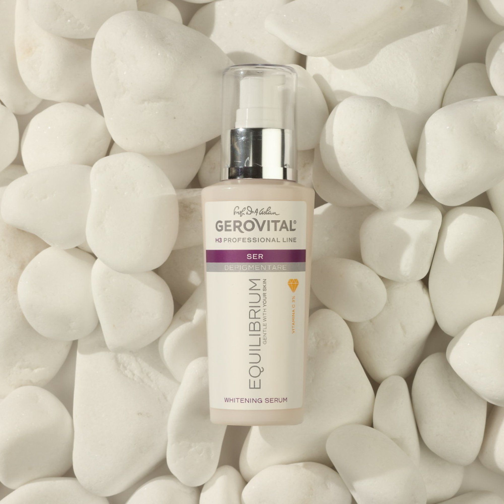 Flacone di siero con erogatore argento. Scritta: Gerovital, Equilibrium, Vitamina C. Posizionato su pietre bianche.