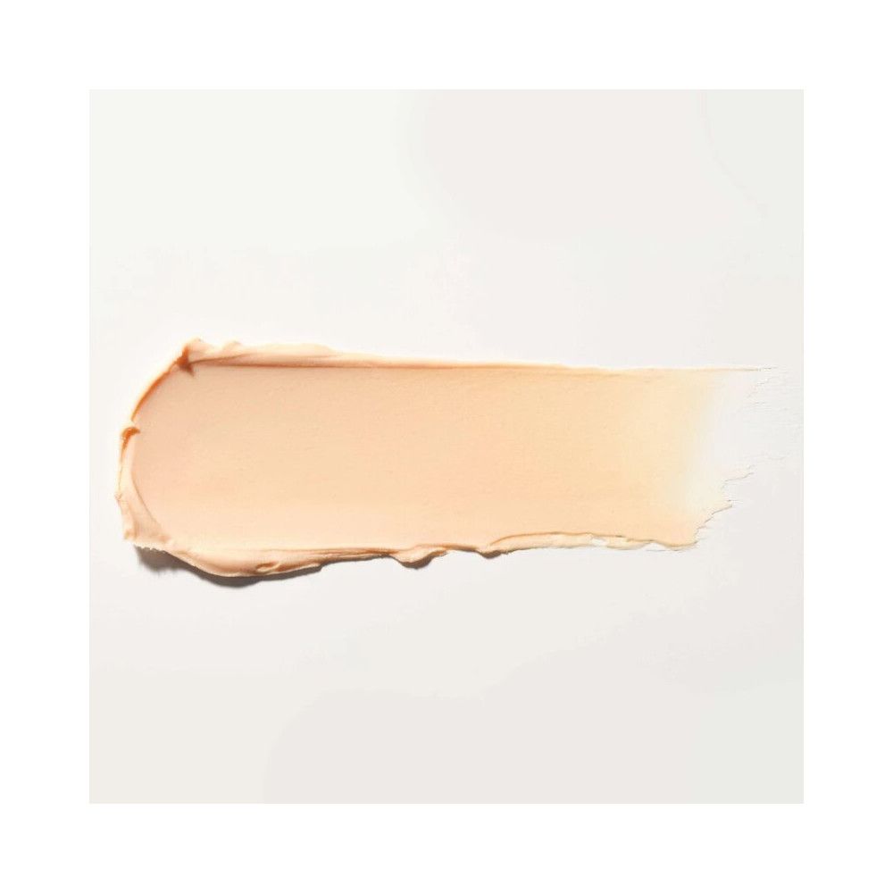 Una striscia di balsamo per le labbra color crema su sfondo bianco. La consistenza è liscia e cremosa.