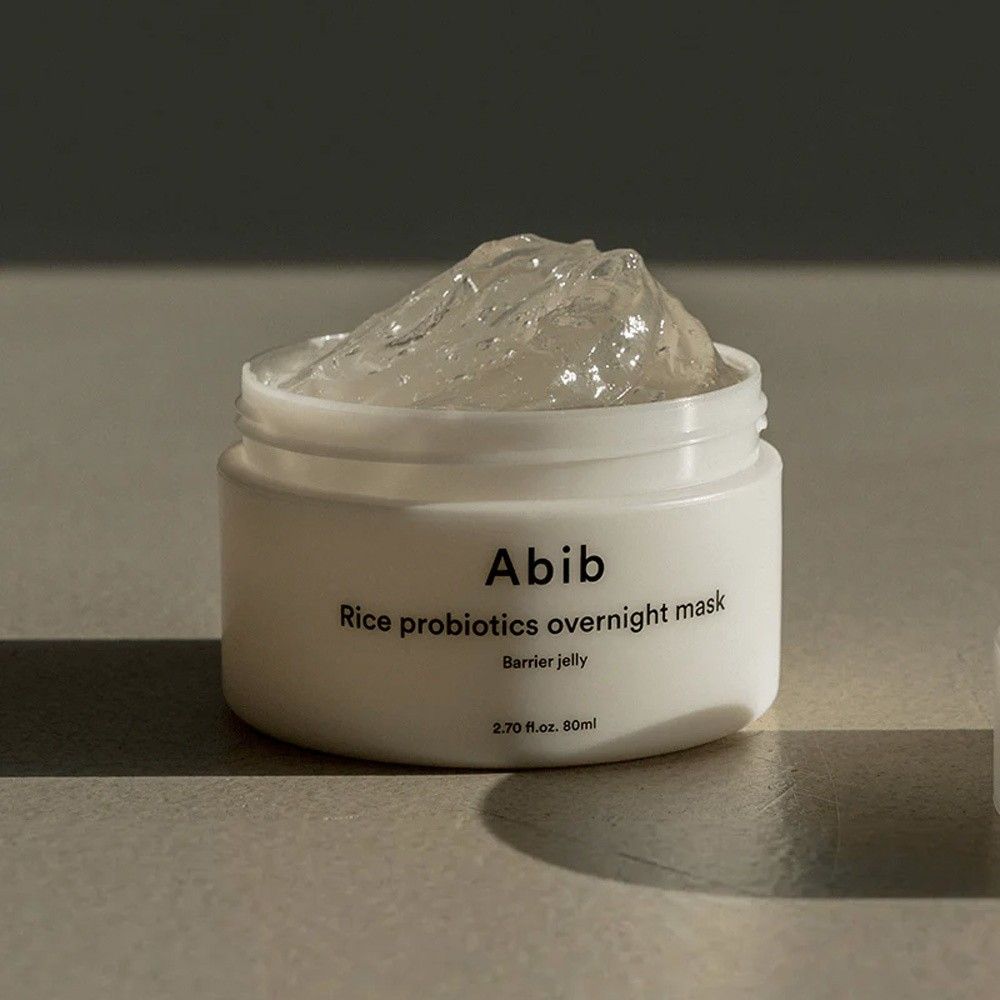 Barattolo bianco aperto con una texture di maschera in gel trasparente.