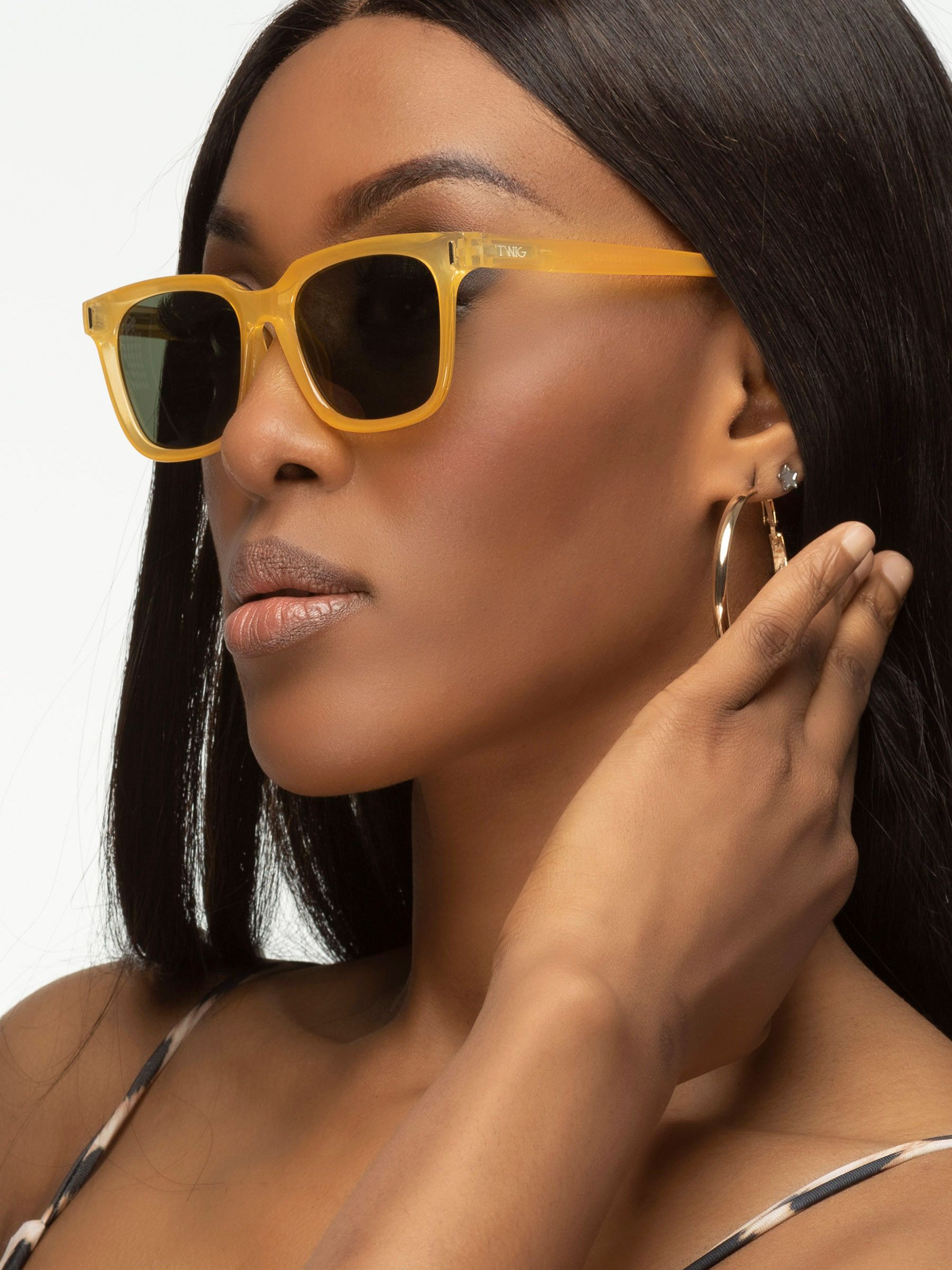 Donna con occhiali da sole gialli. Forma rettangolare, lenti scure. Primo piano.