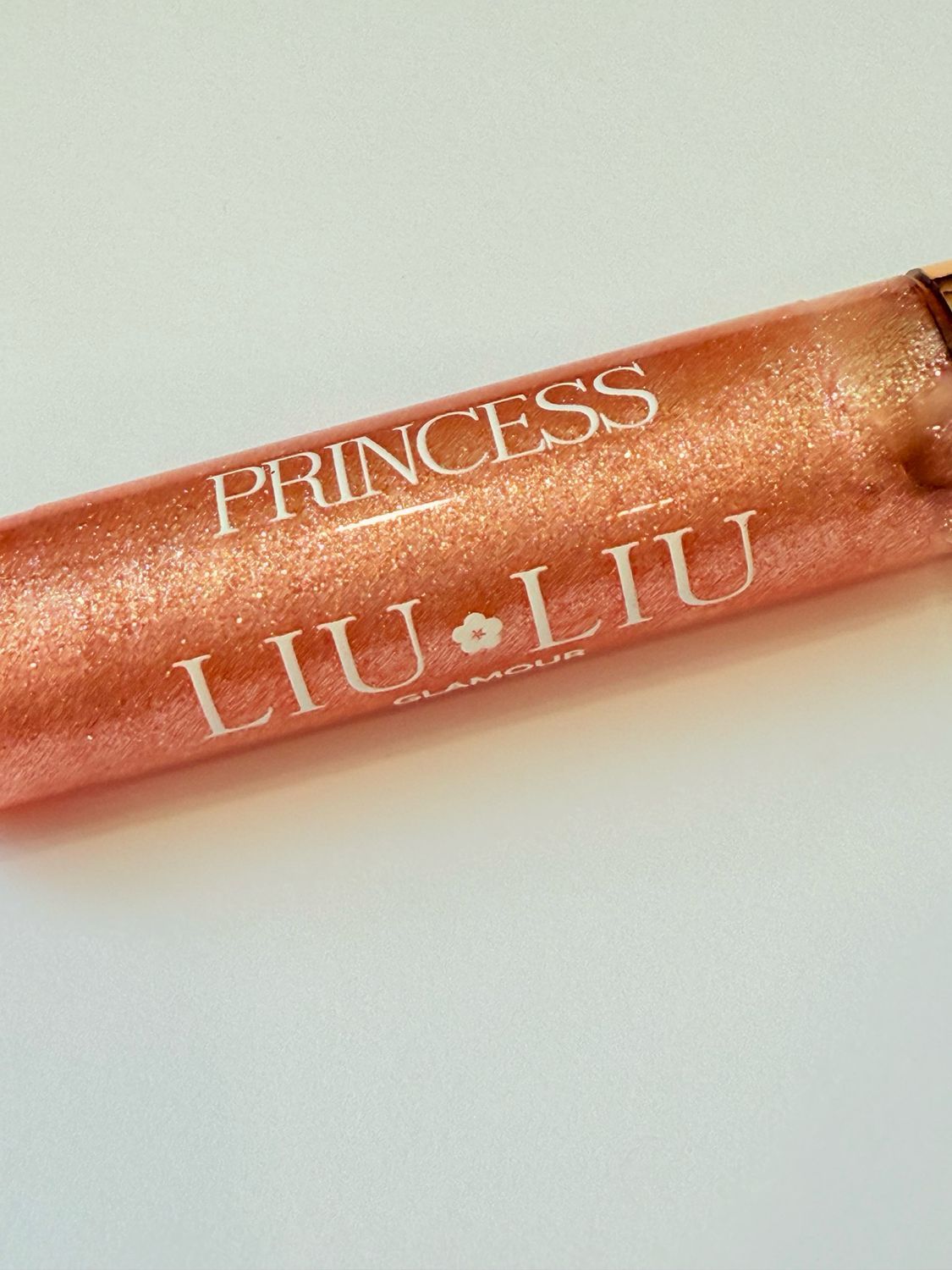 Lucidalabbra con tappo dorato. Scritta: PRINCESS LIU LIU Glamour. Lucidalabbra rosa glitterato. Sfondo bianco.