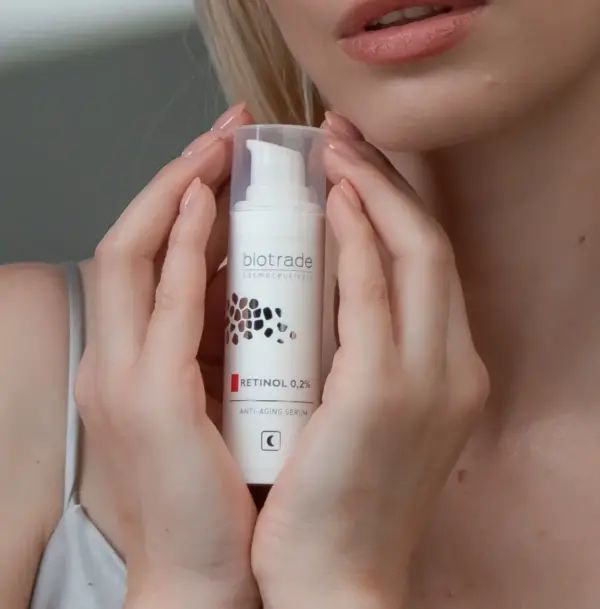 Flacone siero in mani. Scritta: Biotrade, Retinol 0,2%, Anti-Aging Serum. Flacone bianco con dosatore a pompa.